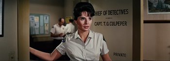 Movie still from “It's a Mad Mad Mad Mad World” (1963), directed by Stanley Kramer – A woman in a uniform is standing in front of a wall; Medium shot, Low angle