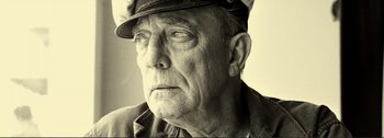 An older man wearing a hat and looking at the camera
