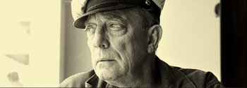 An older man wearing a hat and looking at the camera