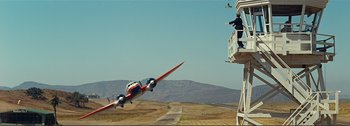 Movie still from “It's a Mad Mad Mad Mad World” (1963), directed by Stanley Kramer – An airplane is flying low to the ground near a building; Extreme Wide shot, Low angle