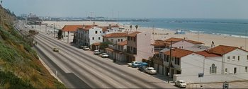 Movie still from “It's a Mad Mad Mad Mad World” (1963), directed by Stanley Kramer – An aerial view of an ocean side city with cars parked on the side of the road; Extreme Wide shot, High angle