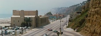 Movie still from “It's a Mad Mad Mad Mad World” (1963), directed by Stanley Kramer – An empty street with cars driving down the road; Extreme Wide shot, High angle