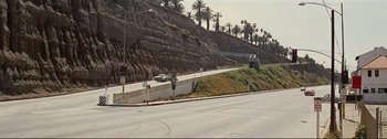 Movie still from “It's a Mad Mad Mad Mad World” (1963), directed by Stanley Kramer – A car driving down a street next to a hill; Extreme Wide shot, High angle