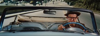 Movie still from “It's a Mad Mad Mad Mad World” (1963), directed by Stanley Kramer – A man in a hat is driving a car; Medium shot, High angle