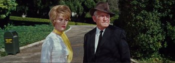 Movie still from “It's a Mad Mad Mad Mad World” (1963), directed by Stanley Kramer – An older man and a young woman standing next to each other on the side of the road; Medium shot, Low angle