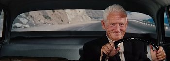 Movie still from “It's a Mad Mad Mad Mad World” (1963), directed by Stanley Kramer – An older man sitting in a car wearing a suit and tie; Close Up shot, Low angle