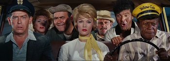 Movie still from “It's a Mad Mad Mad Mad World” (1963), directed by Stanley Kramer – A woman sitting in the back seat of a car with two men behind her; Medium shot, Low angle