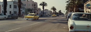 Movie still from “It's a Mad Mad Mad Mad World” (1963), directed by Stanley Kramer – A street scene with cars driving down the road and palm trees in the background; Extreme Wide shot, Low angle