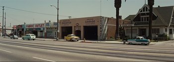 Movie still from “It's a Mad Mad Mad Mad World” (1963), directed by Stanley Kramer – A yellow truck parked in front of a garage; Extreme Wide shot, High angle