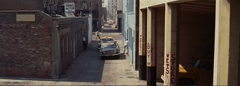 Movie still from “It's a Mad Mad Mad Mad World” (1963), directed by Stanley Kramer – A car parked on the side of the road in an alleyway; Extreme Wide shot, High angle