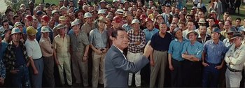 Movie still from “It's a Mad Mad Mad Mad World” (1963), directed by Stanley Kramer – A group of men standing in front of each other wearing hats; Medium shot, High angle