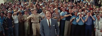 Movie still from “It's a Mad Mad Mad Mad World” (1963), directed by Stanley Kramer – A man in a suit and hat is in front of a group of men; Medium shot, High angle