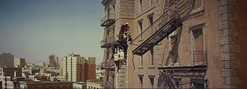 Movie still from “It's a Mad Mad Mad Mad World” (1963), directed by Stanley Kramer – A group of people climbing a fire escape on the side of a building; Extreme Wide shot, High angle