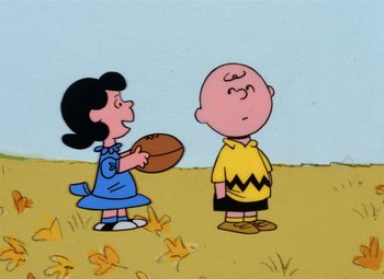 Movie still from “It's the Great Pumpkin, Charlie Brown” (1966), directed by Bill Melendez – A charlie brown and a girl holding a football in a field; Extreme Wide shot, High angle