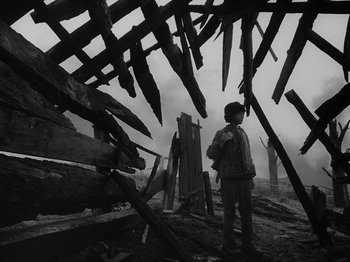 Movie still from “Ivan's Childhood” (1962), directed by Eduard Abalov – A man standing in front of a pile of wood; Wide shot, Low angle