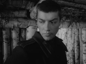 Movie still from “Ivan's Childhood” (1962), directed by Eduard Abalov – A man in a black jacket is standing in front of a wall; Close Up shot, Over the shoulder angle