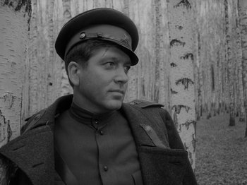 Movie still from “Ivan's Childhood” (1962), directed by Eduard Abalov – A man wearing a uniform and a hat in front of trees; Close Up shot, Low angle