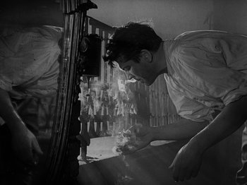 Movie still from “Ivan's Childhood” (1962), directed by Eduard Abalov – An old photo of a man working on something; Medium shot, Low angle