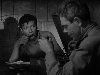 Movie still from “Ivan's Childhood” (1962), directed by Eduard Abalov – Two men are sitting at a table and one of them is eating; Medium shot, Over the shoulder angle