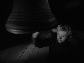 Movie still from “Ivan's Childhood” (1962), directed by Eduard Abalov – A young boy is looking up at a large bell; Close Up shot, High angle