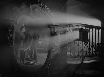 Movie still from “Ivan's Childhood” (1962), directed by Eduard Abalov – A person standing in front of a mirror in a room; Wide shot, Low angle