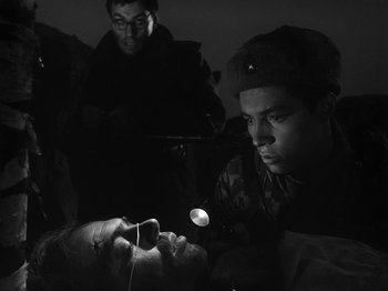 Movie still from “Ivan's Childhood” (1962), directed by Eduard Abalov – A man is looking down at something in his hand; Close Up shot, Low angle