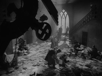 A black and white photo of people in a room with papers