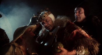 Movie still from “Jabberwocky” (1977), directed by Terry Gilliam – Two men in medieval garb are holding fruit and a knife; Medium shot, Low angle