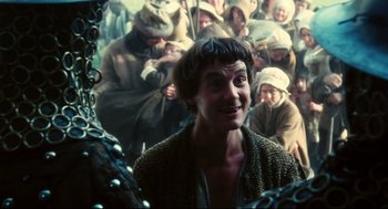 Movie still from “Jabberwocky” (1977), directed by Terry Gilliam – A group of people gathered around a man with a beard; Medium shot, Over the shoulder angle