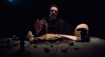 Movie still from “Jabberwocky” (1977), directed by Terry Gilliam – A man sitting at a dinner table with a knife and fork; Medium shot, High angle