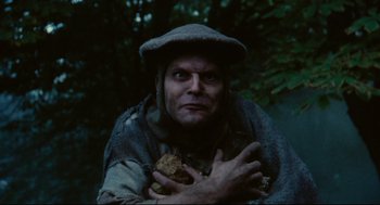 Movie still from “Jabberwocky” (1977), directed by Terry Gilliam – A man holding a piece of food in his hands; Close Up shot, Low angle