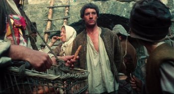 Movie still from “Jabberwocky” (1977), directed by Terry Gilliam – A group of people standing around a basket; Medium shot, Low angle