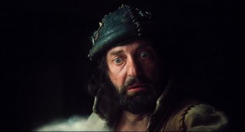 Movie still from “Jabberwocky” (1977), directed by Terry Gilliam – A person with a beard wearing a hat; Close Up shot, Low angle