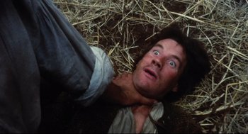 Movie still from “Jabberwocky” (1977), directed by Terry Gilliam – A man laying on the ground looking up at the camera; Close Up shot, Overhead angle