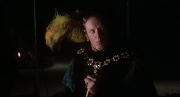 Movie still from “Jabberwocky” (1977), directed by Terry Gilliam – A man in a costume with a bird on his head; Close Up shot, Over the shoulder angle