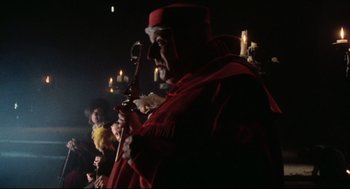 Movie still from “Jabberwocky” (1977), directed by Terry Gilliam – A man in a red robe holding a sword; Medium shot, Low angle