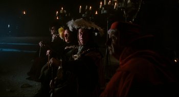 Movie still from “Jabberwocky” (1977), directed by Terry Gilliam – A group of people dressed up in costumes and hats; Wide shot, High angle