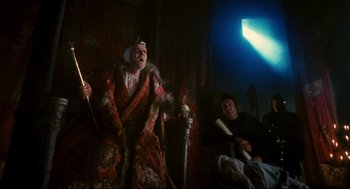 Movie still from “Jabberwocky” (1977), directed by Terry Gilliam – Two men sitting on a chair and one is holding a cane; Wide shot, Low angle