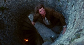 Movie still from “Jabberwocky” (1977), directed by Terry Gilliam – A man climbing up a spiral staircase in a cave; Medium shot, Overhead angle