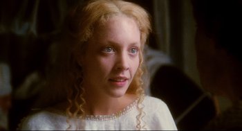 Movie still from “Jabberwocky” (1977), directed by Terry Gilliam – A woman with blonde curly hair wearing a white dress; Close Up shot, Over the shoulder angle