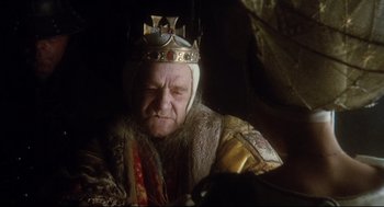 Movie still from “Jabberwocky” (1977), directed by Terry Gilliam – An old man wearing a crown and a gold robe; Close Up shot, Over the shoulder angle