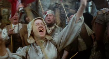 Movie still from “Jabberwocky” (1977), directed by Terry Gilliam – A man and a woman in medieval garb are cheering; Medium shot, Low angle
