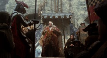 Movie still from “Jabberwocky” (1977), directed by Terry Gilliam – A man dressed as a wizard in front of a crowd; Wide shot, Low angle