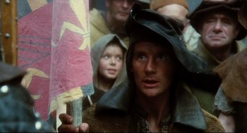Movie still from “Jabberwocky” (1977), directed by Terry Gilliam – A man holding an umbrella in front of a crowd of onlookers; Close Up shot, Low angle
