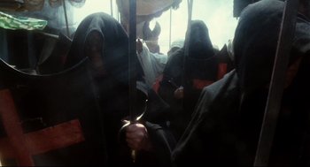 Movie still from “Jabberwocky” (1977), directed by Terry Gilliam – A group of people riding on a bus with umbrellas; Medium shot, High angle