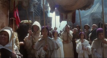 Movie still from “Jabberwocky” (1977), directed by Terry Gilliam – A group of people dressed in medieval clothing; Wide shot, High angle