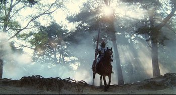 Movie still from “Jabberwocky” (1977), directed by Terry Gilliam – A man riding on the back of a horse through the woods; Extreme Wide shot, Low angle