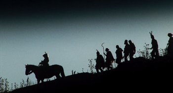 Movie still from “Jabberwocky” (1977), directed by Terry Gilliam – A group of people on horseback walking up a hill at night; Extreme Wide shot, Low angle