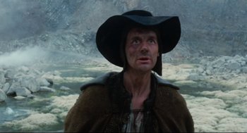 Movie still from “Jabberwocky” (1977), directed by Terry Gilliam – A man wearing a black hat and a brown jacket; Medium shot, Low angle
