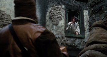 Movie still from “Jabberwocky” (1977), directed by Terry Gilliam – A man is looking out of a window at another man; Medium shot, Over the shoulder angle